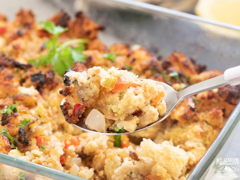 Oyster stuffing is served in a deep dish with a silver spoon. 