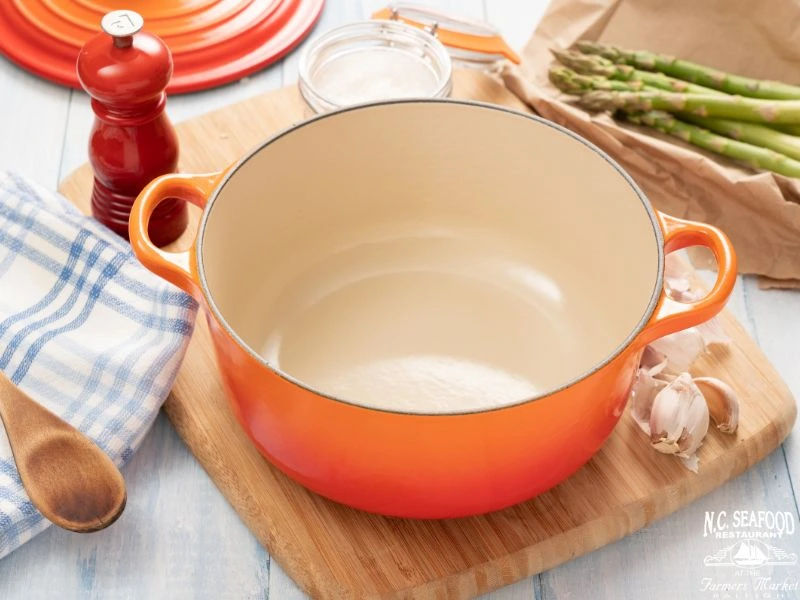 A photo of a Dutch oven on a wood cutting board. This is for the blog titled "Dairy Free Clam Chowder."